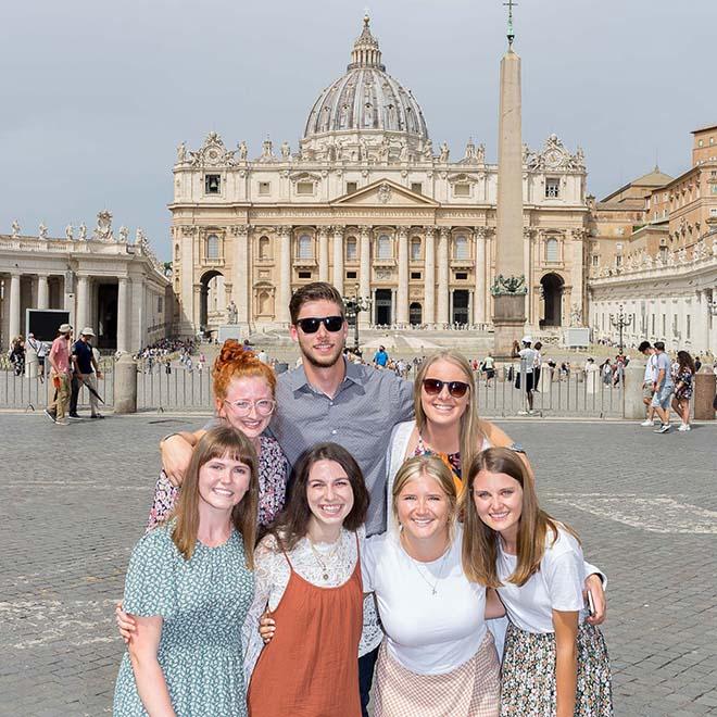 Group of smiling study abroad students in front of St. Peter’s Basilica in Rome