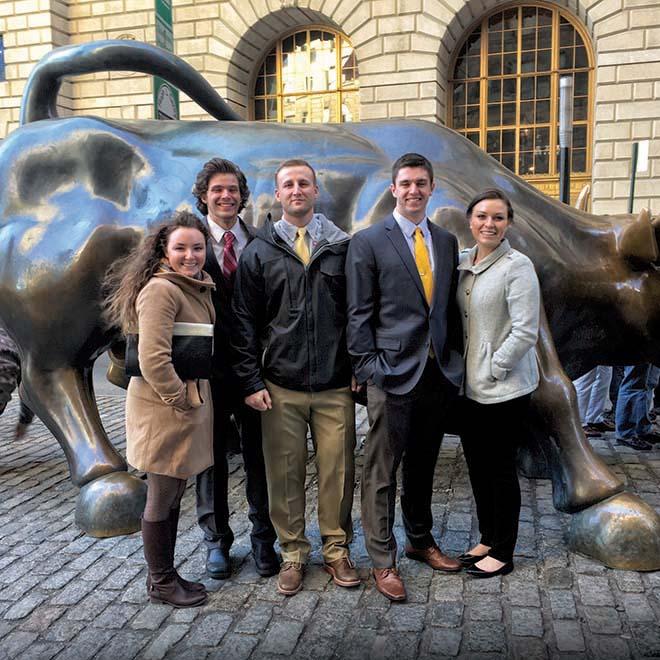 Group of investment club students in front of the Charging Bull in New York City