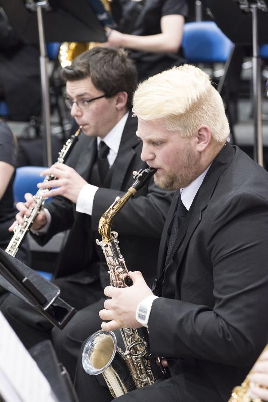 Two men playing saxophone in concert band.