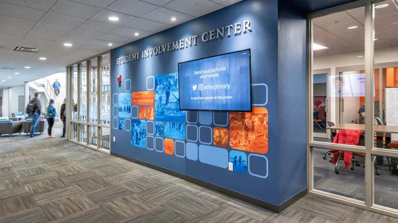 A view from outside the Student Involvement Center with students sitting inside and walking in the distance