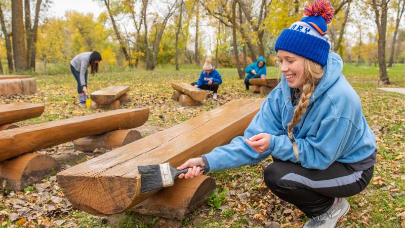 Female student painting a bench during day of service.