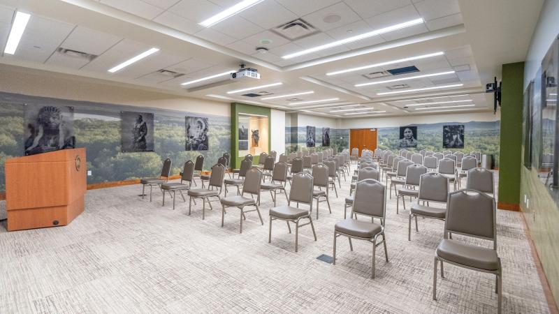 The Apple Creek Conference Room setup for a presentation features wet-plate photos of Native Americans overlaying a wall wrap of the Missouri River Valley.