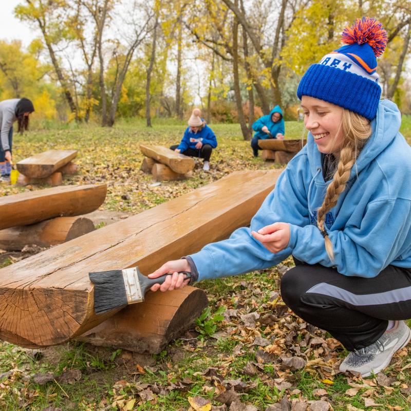 Female student painting a bench during day of service.