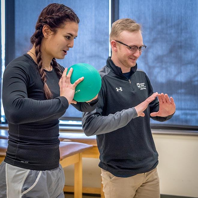 Athletic training student showing athlete proper throwing movement