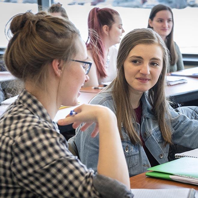 Happy female students having a conversation in class