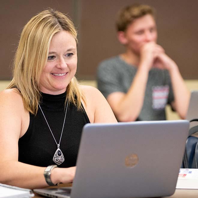 Smiling adult student in evening class on laptop