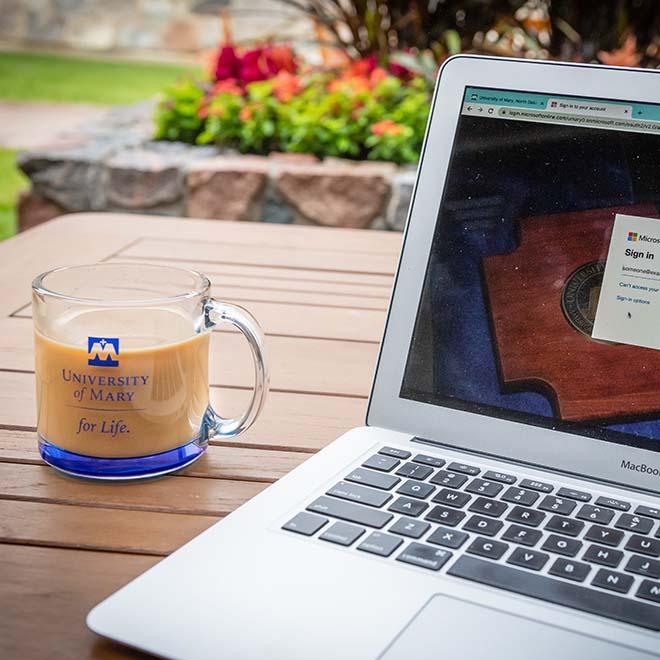 Glass coffee cup on an outdoor patio table near an open laptop