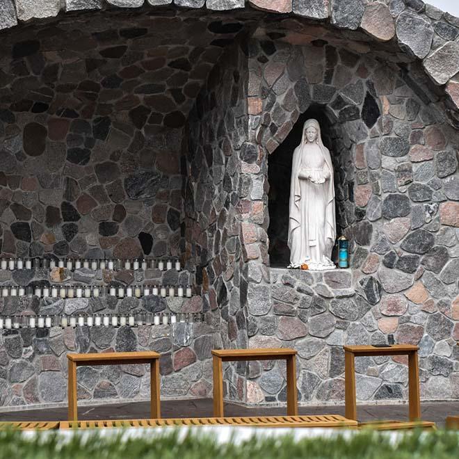 A closeup of grotto with candles and statue of Mary