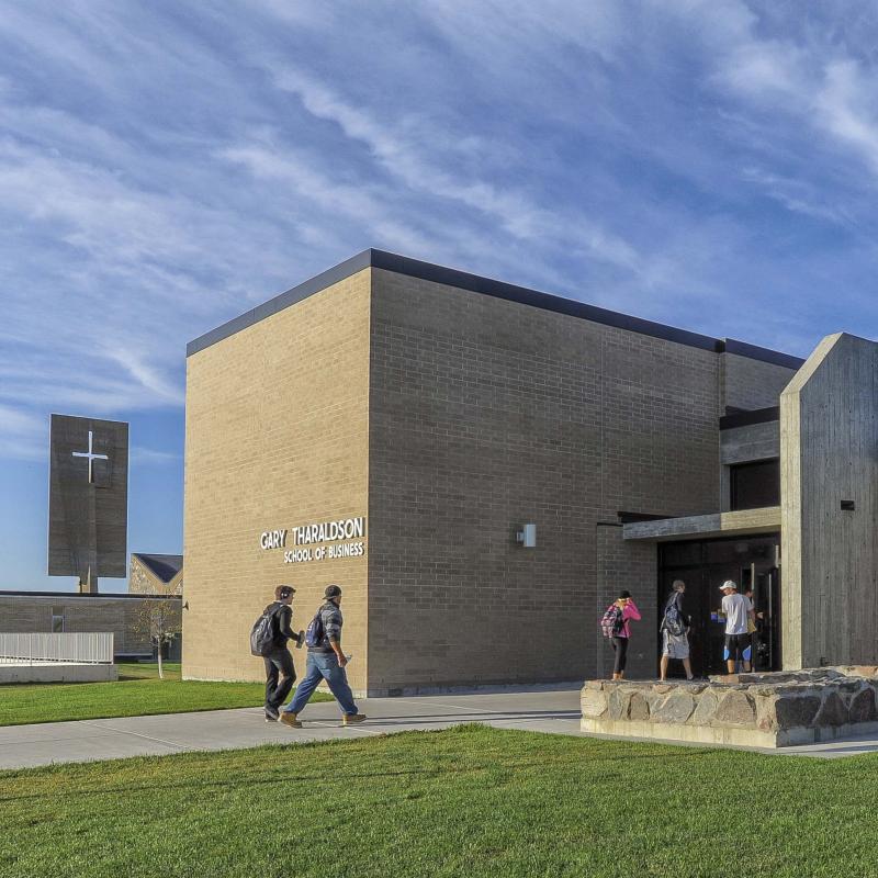 Five students walking into the Gary Tharaldson School of Business