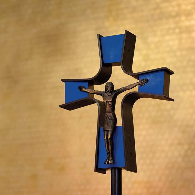 Closeup of crucifix in Our Lady of the Annunciation Chapel with a gold leaf wall in the background.