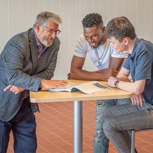 Dr. Karel Sovak meeting with two male students.