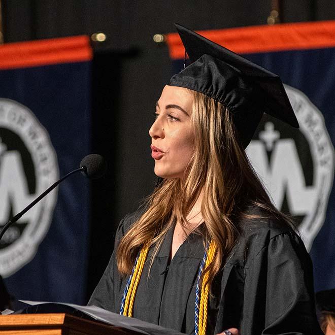 Female graduate speaking on stage at commencement