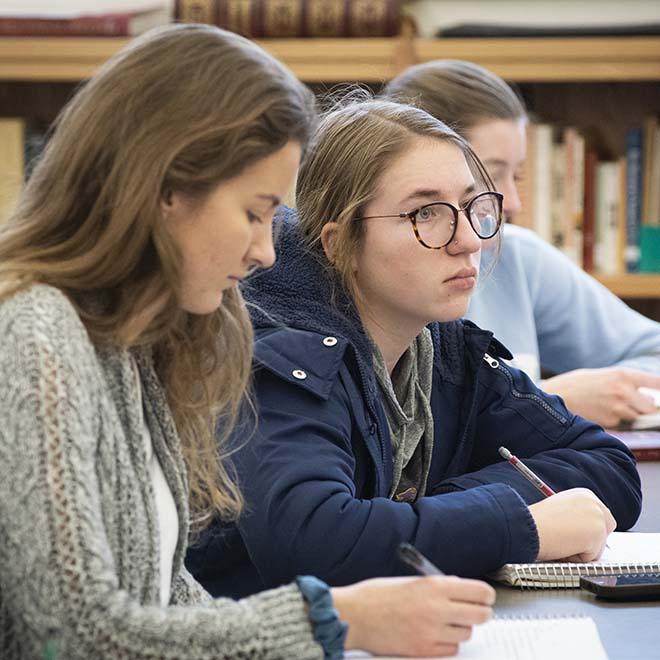 Two female students taking notes during lecture