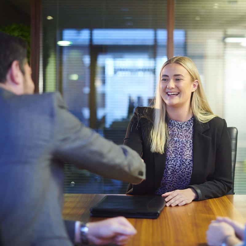 Smiling interviewee shaking hands with interviewer