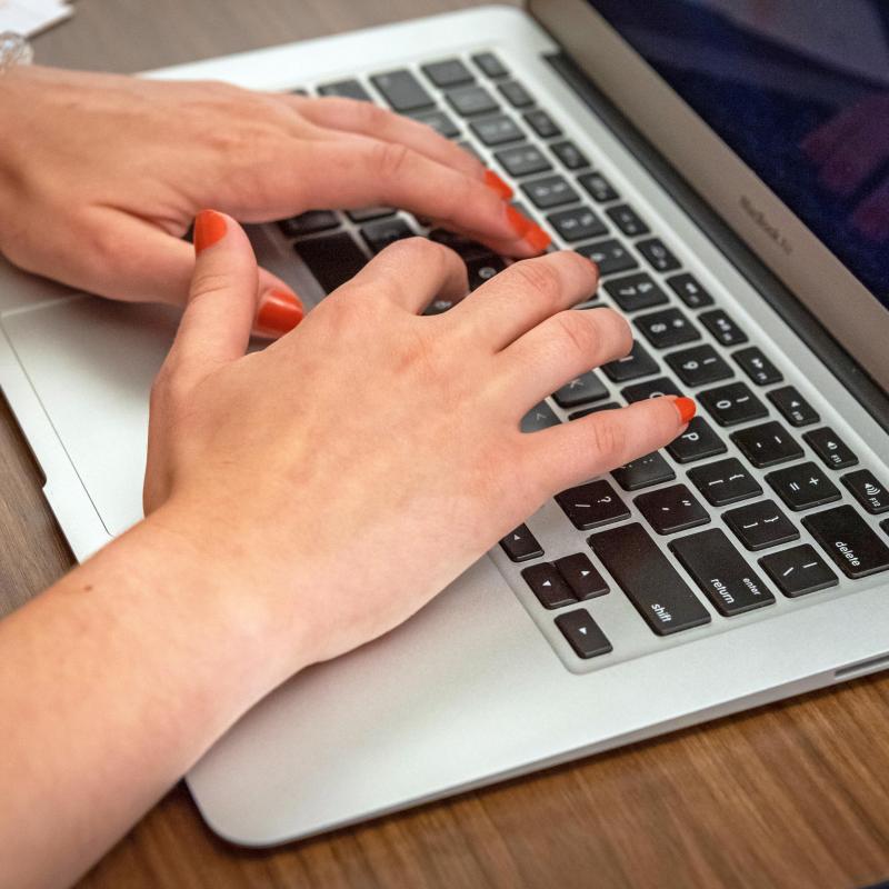 Hands typing on a laptop.