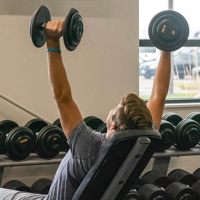 Student lifting weights in the fitness center.