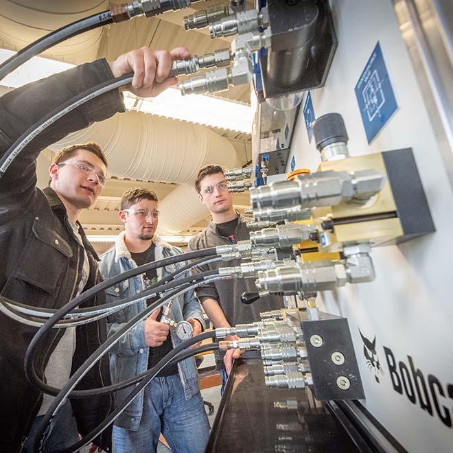 Engineering students working on Bobcat machinery