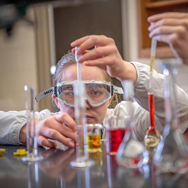 SURVE student dropping chemicals into a beaker.