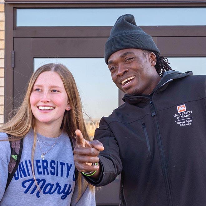 Campus safety and security employee pointing and giving a University of Mary student directions.