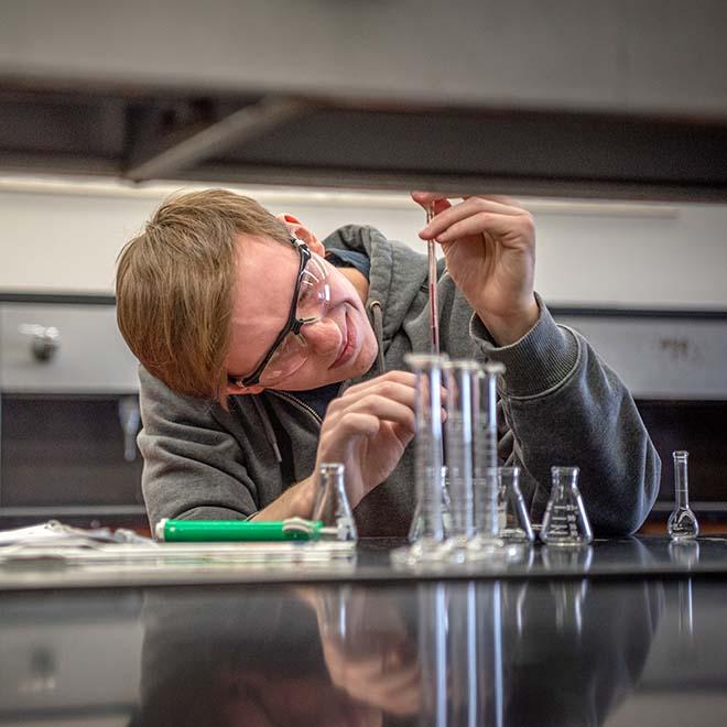 Chemistry student dropping chemicals into beeker