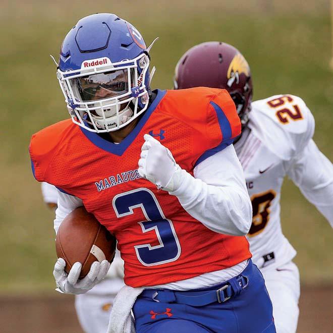 Marauders football player running with football and breaking away from defender.