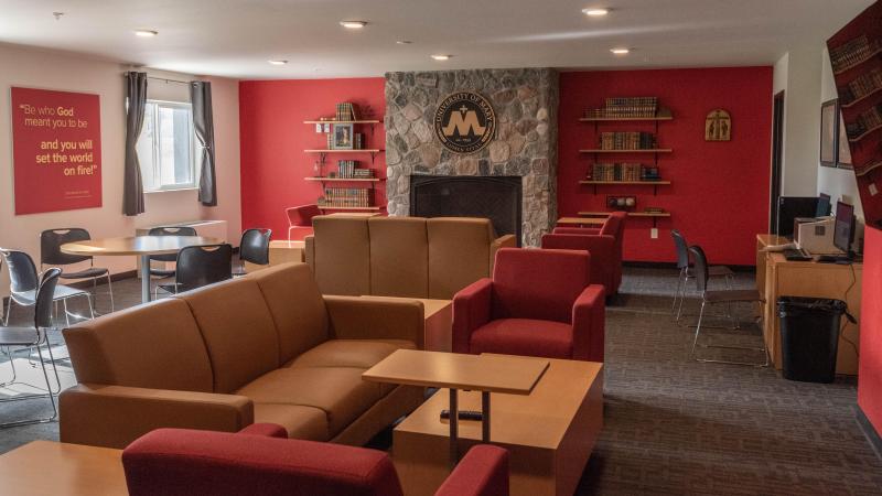 Living room set up in Roers Hall featuring a fireplace, couches, and tables.