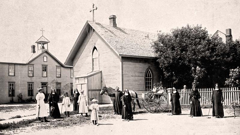 A photo from 1878 of religious people standing outside church and in front of horse drawn carriage.
