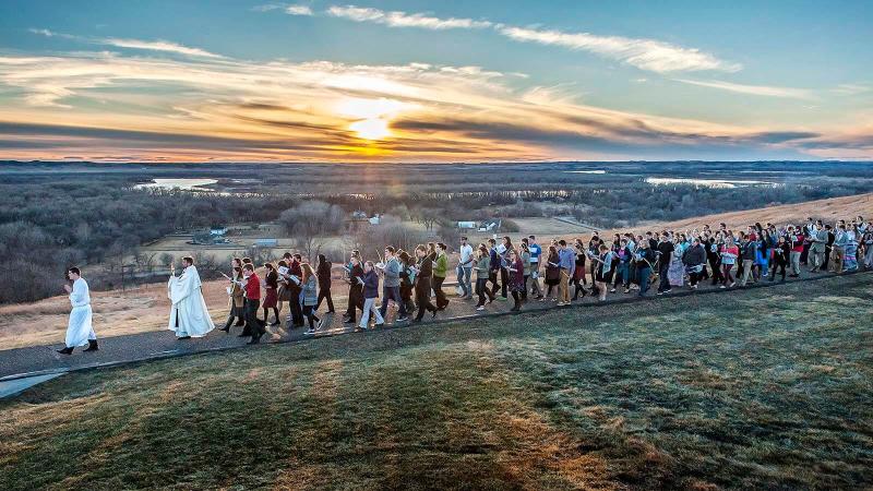 Young people following a Palm Sunday processional at sunset.