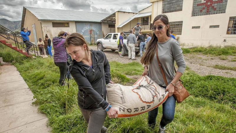 Two female volunteers in Peru delivering bags of rice.
