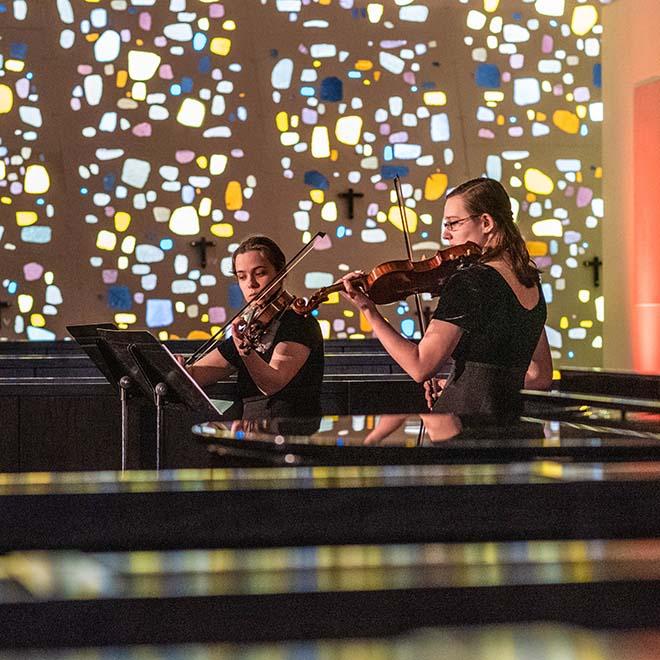 Two string musicians playing in the Our Lady of the Annunciation Chapel