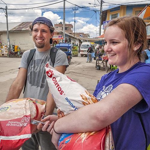 Two students carrying flour during a service trip in Peru.