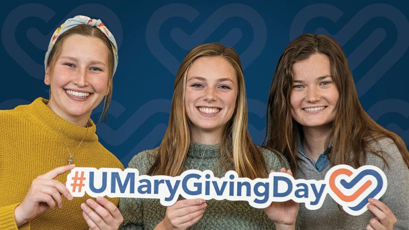 Three female students with the #UMary giving day sign