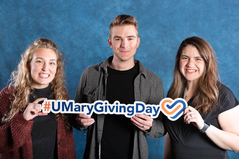 Three students with the #UMary giving day sign