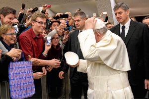 ​​​​​​​University of Mary Rome Campus student Chris Riedman (in red shirt) gets ready to exchange zucchettos with Pope Francis