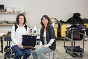 ​​​​​​​R.Riveter cofounders Cameron Cruse (left) and Lisa Bradley (right) show one of their handbags in their shop.