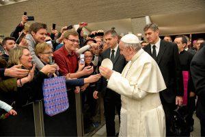 ​​​​​​​Pope Francis gets ready to size up the zucchetto he is about to exchange with University of Mary Rome Campus student Chris Riedman (in red shirt). This papal occurrence was made popular by Pope Saint John Paul II.