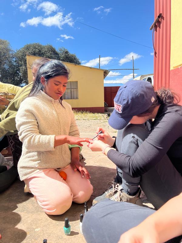 Students in Peru painting a child's nails