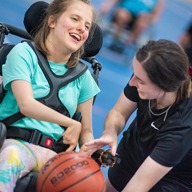Students working with kids with Disabilities playing basketball
