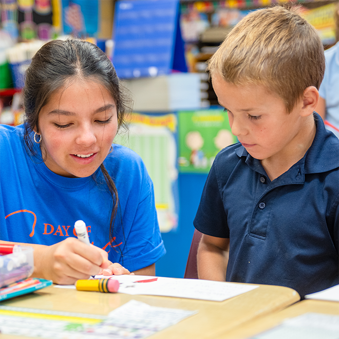 A female students working with a young male child coloring.