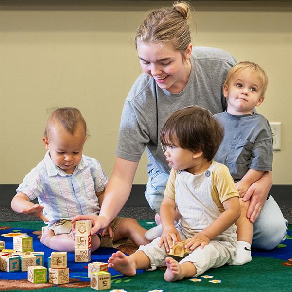 teacher playing blocks with three little kids