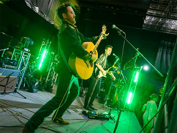 Joe Berger playing the guitar under green stage lights