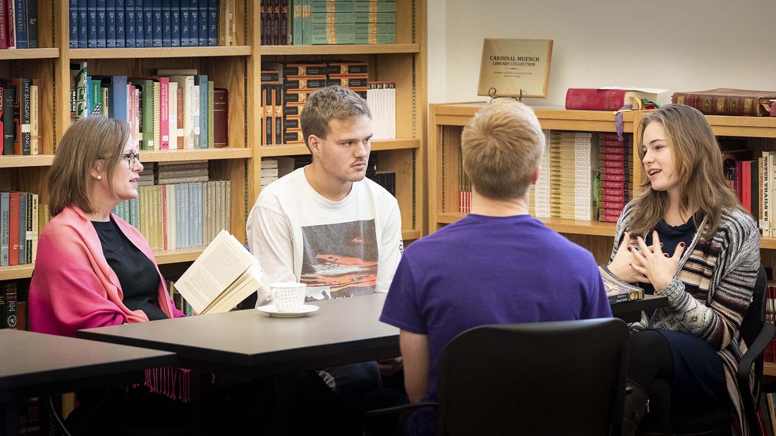 Three Catholic studies students in informal discussion with professor