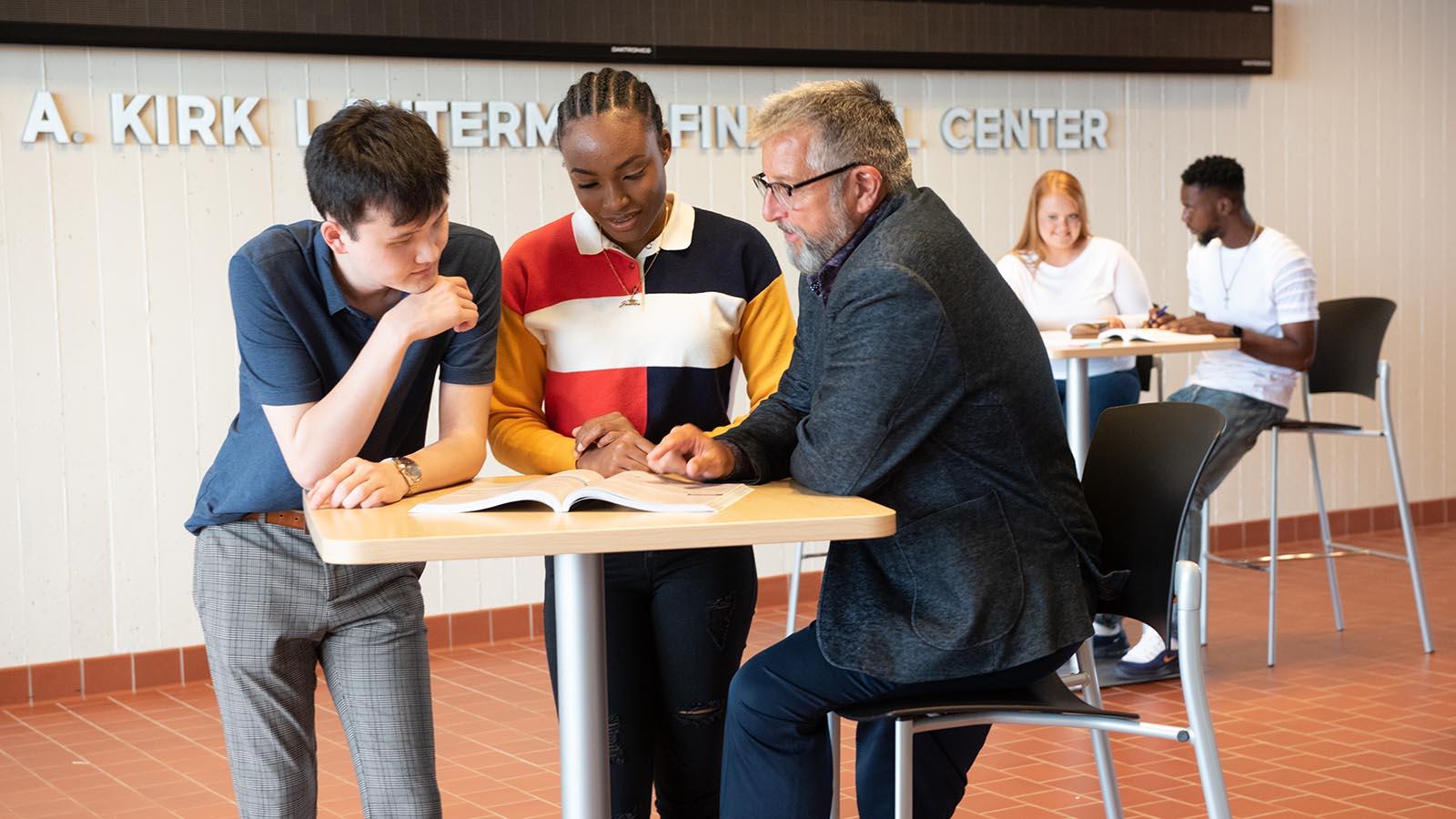 Two business students having a discussion with a professor outside university financial center