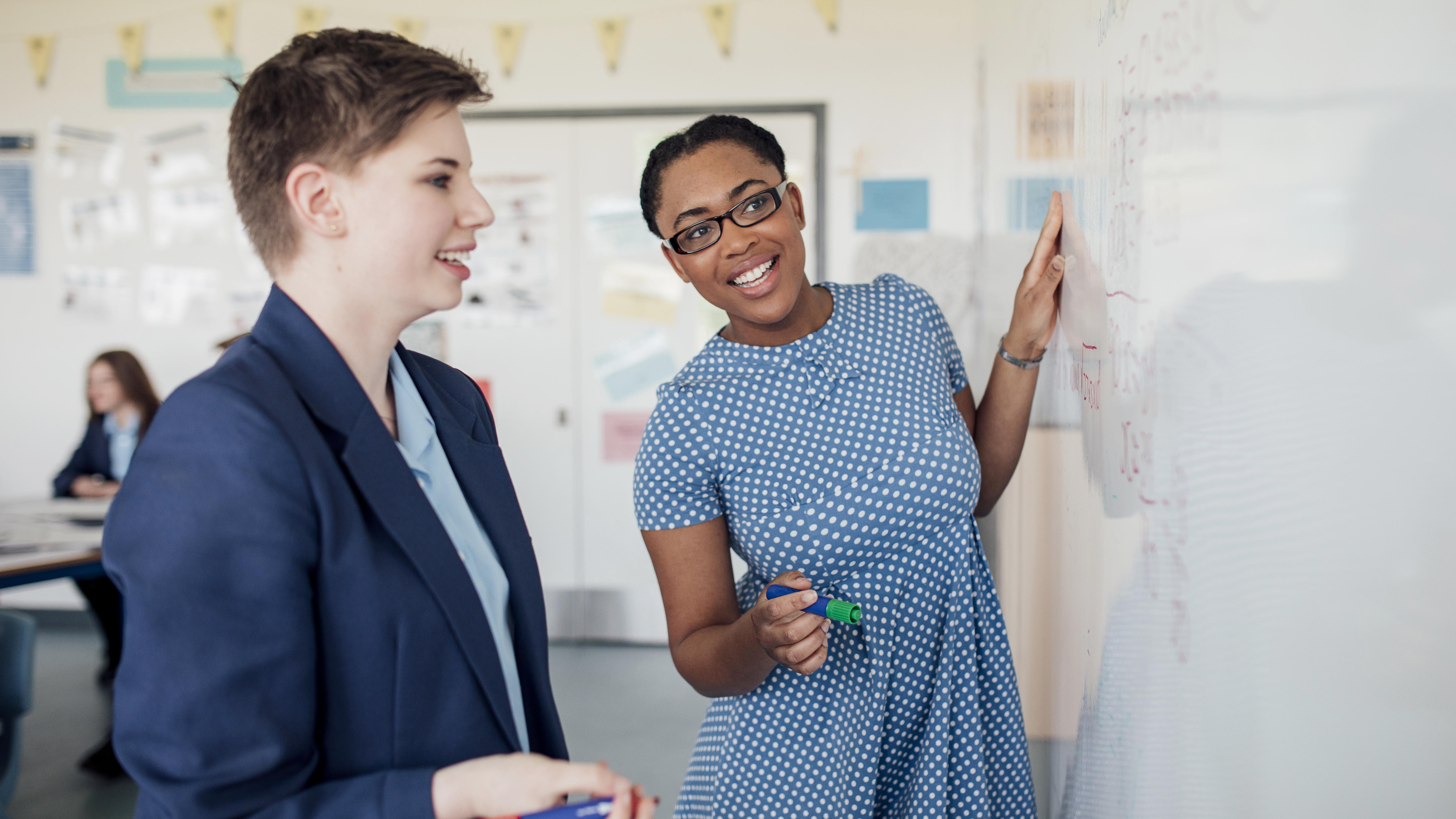 Female English teacher with student at white board.