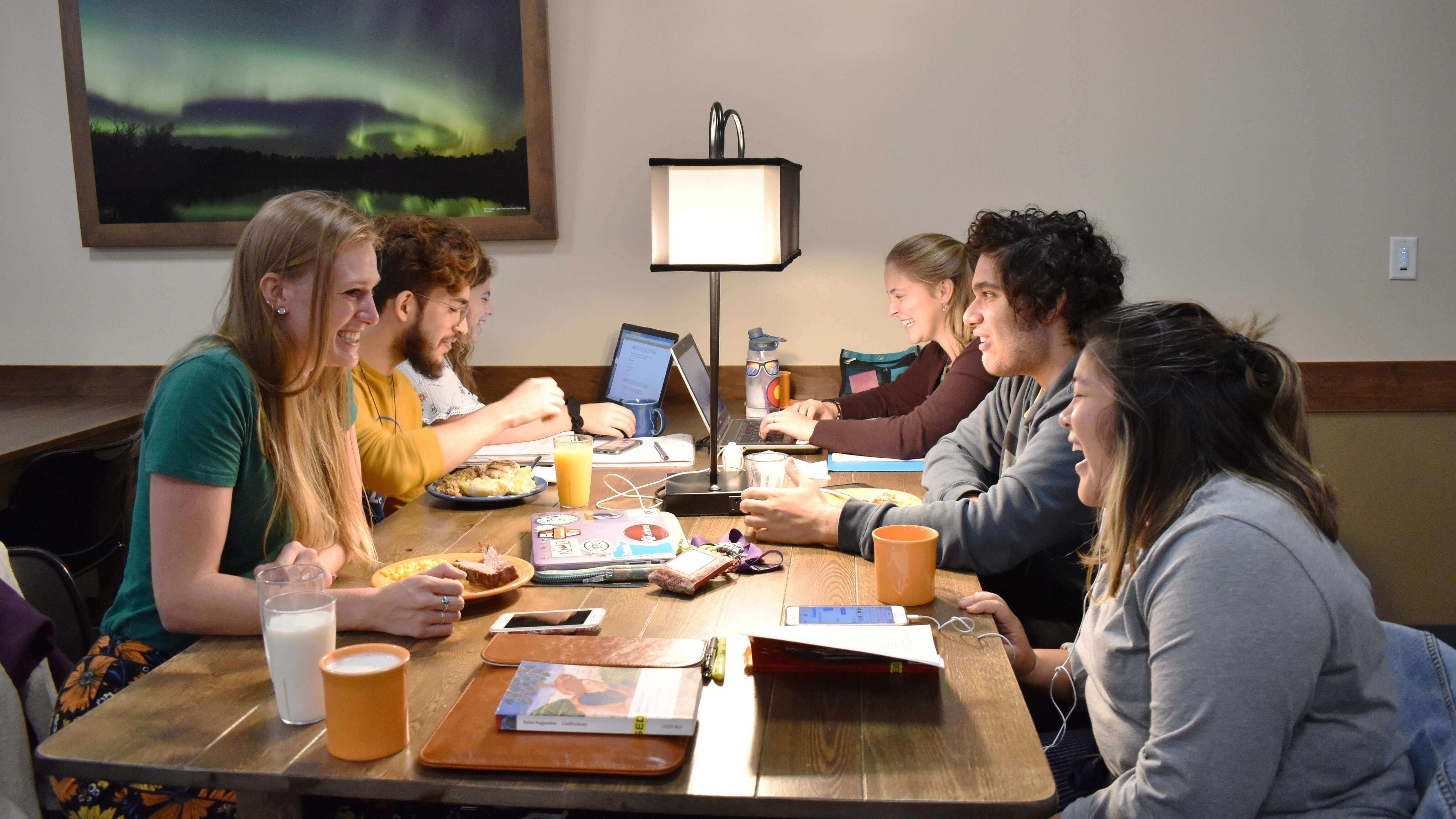 Group of students studying and eating a meal together in the lower level of the Crow’s Nest Campus Restaurant.