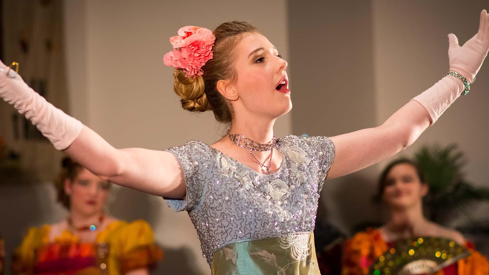 Vocal arts performer on stage with arms spread out to audience