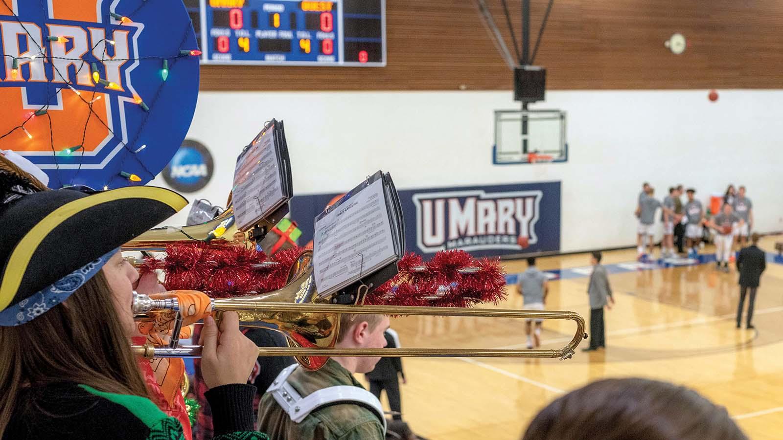 Pep band playing with basketball game in background