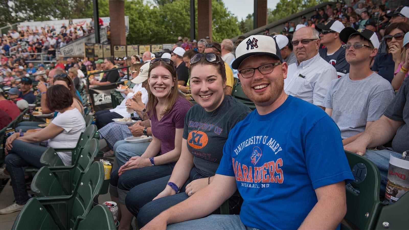 Two Mary alumni sit together at a Bismarck Larks baseball game. 