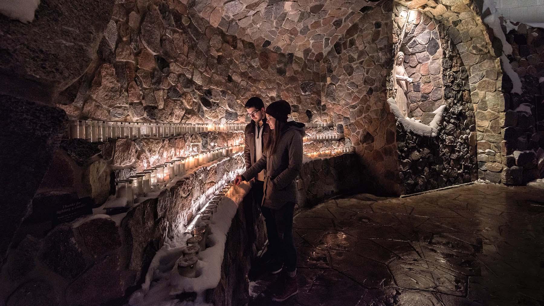 Two students lighting a candle in the grotto 