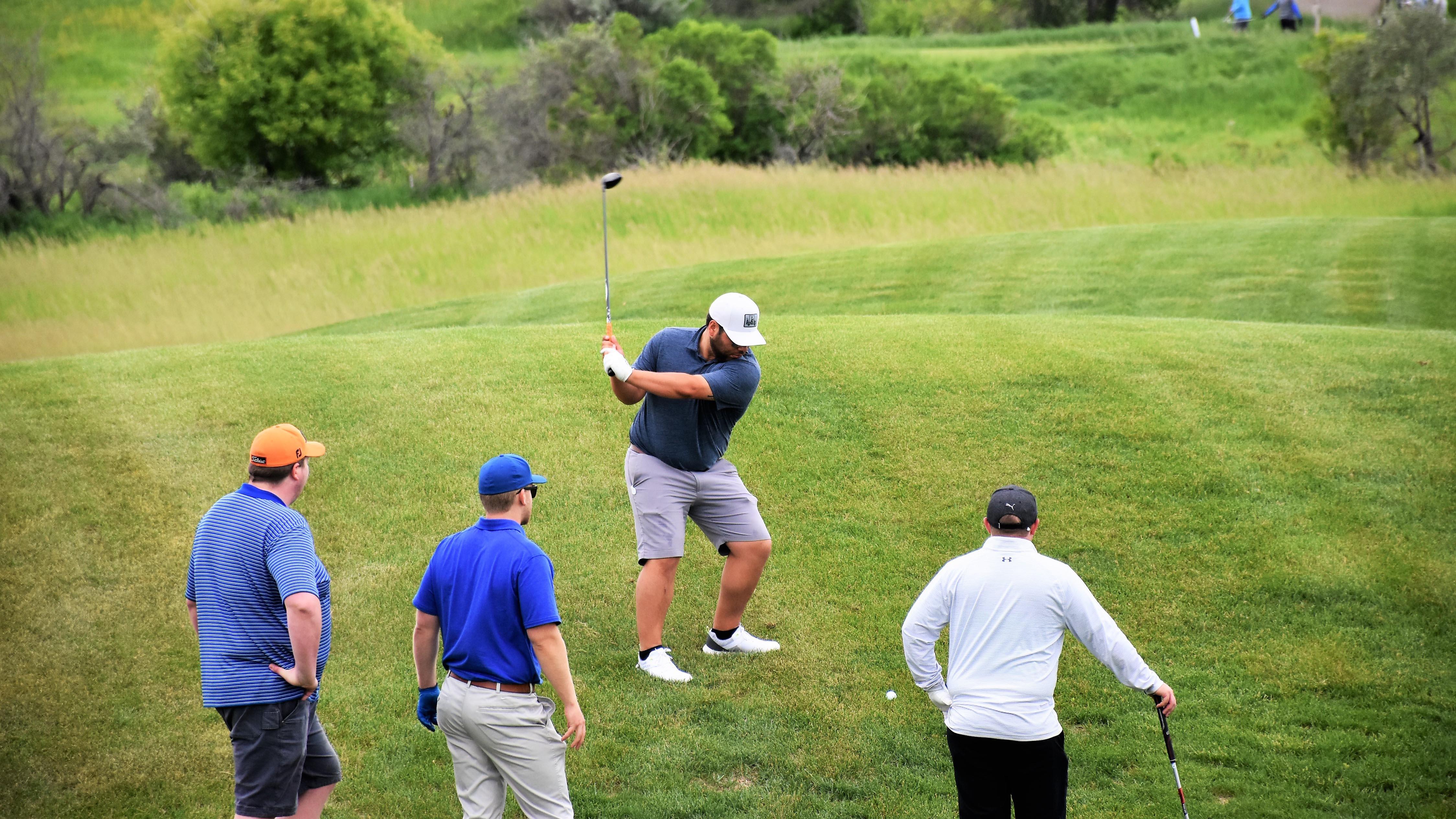 Four men golfing on a green golf course.